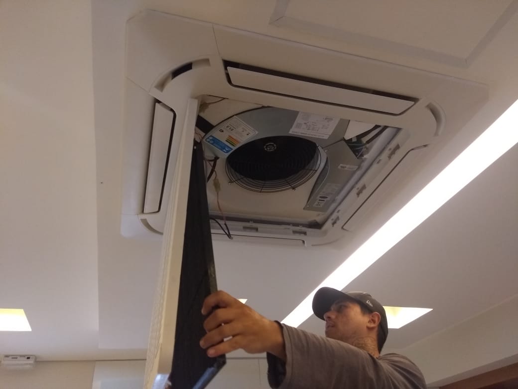 Equipe realizando instalação de ar condicionado em ambiente corporativo